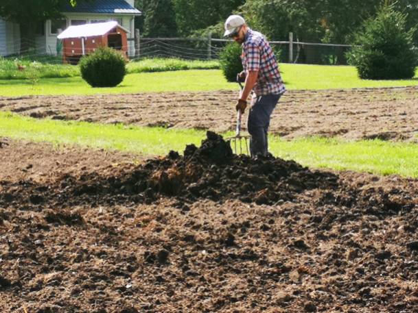 Jesse manually applies composted manure to the field block before seeding cover crops.